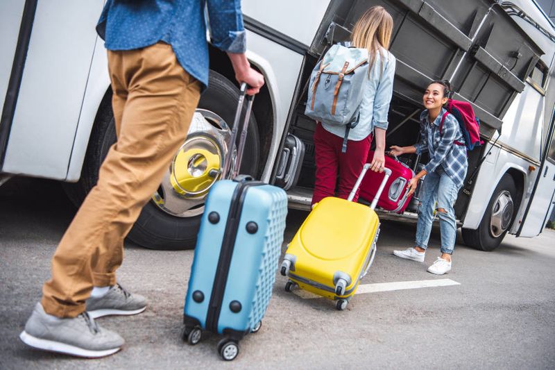 Reisende mit Trolley vor dem Reisebus